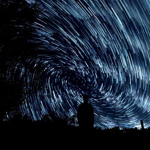 Foto de um homem em pé e um céu estrelado ao fundo